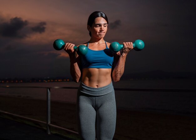 Vooraanzicht fitte vrouw training met dumbells