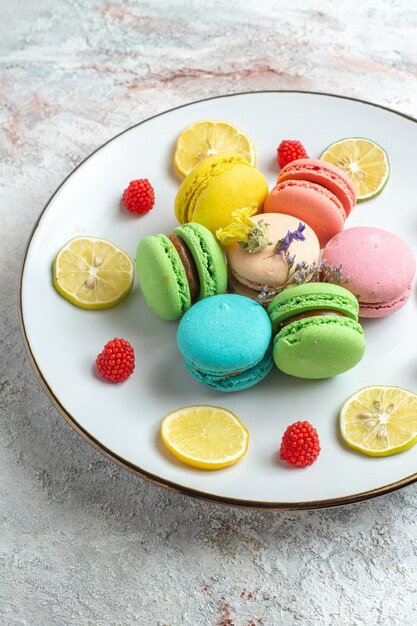 Vooraanzicht franse macarons heerlijke kleine cakes met schijfjes citroen op witte ruimte