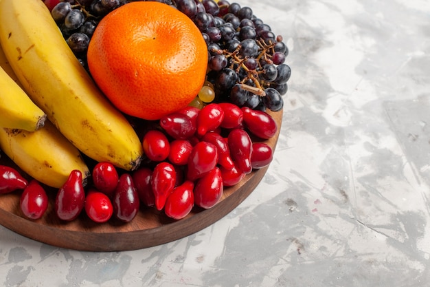 Vooraanzicht fruitsamenstelling bananen kornoeljes en druiven op het witte oppervlak fruit bes versheid vitamine