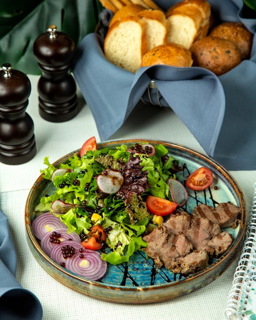 Vooraanzicht gegrild vlees met groentesalade en uien op een dienblad