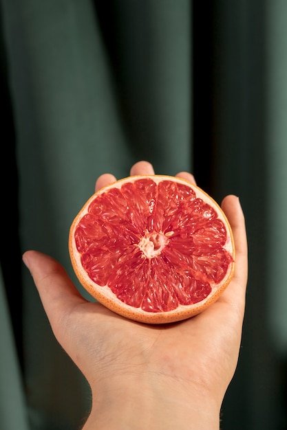 Gratis foto vooraanzicht gehalveerde grapefruit bij de hand