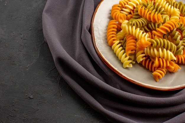 Vooraanzicht gekookte italiaanse pasta ongebruikelijke spiraal pasta binnen plaat op de donkere ruimte