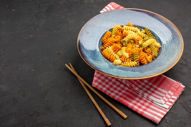 Vooraanzicht gekookte italiaanse pasta ongebruikelijke spiraal pasta binnen plaat op de donkere ruimte