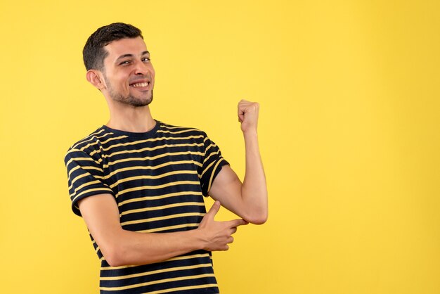 Vooraanzicht gelukkige jonge man in zwart-wit gestreepte t-shirt gele geïsoleerde achtergrond