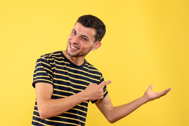 Vooraanzicht gelukkige jonge man in zwart-wit gestreepte t-shirt gele geïsoleerde achtergrond