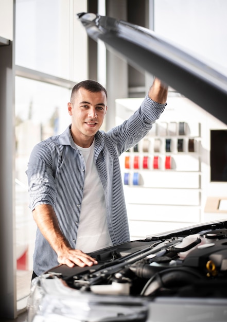 Vooraanzicht gelukkige mens die een auto controleert