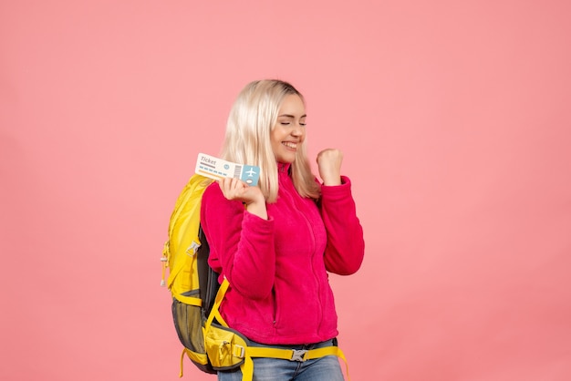 Vooraanzicht gelukkige reizigersvrouw in vrijetijdskleding die het kaartje van de rugzakholding dragen