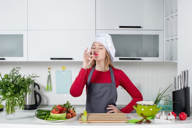 Vooraanzicht gezegende jonge vrouw in schort die chef-kok kusteken maakt