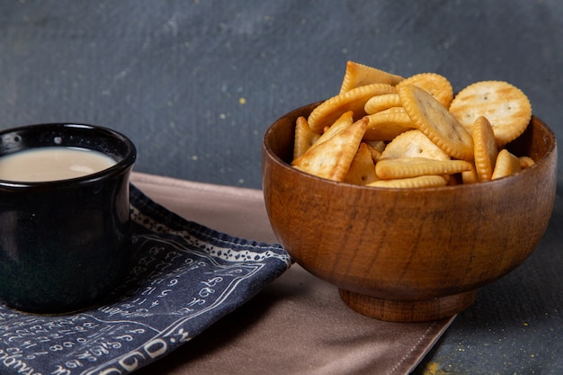 Vooraanzicht gezouten chips met zwarte kop melk op grijs