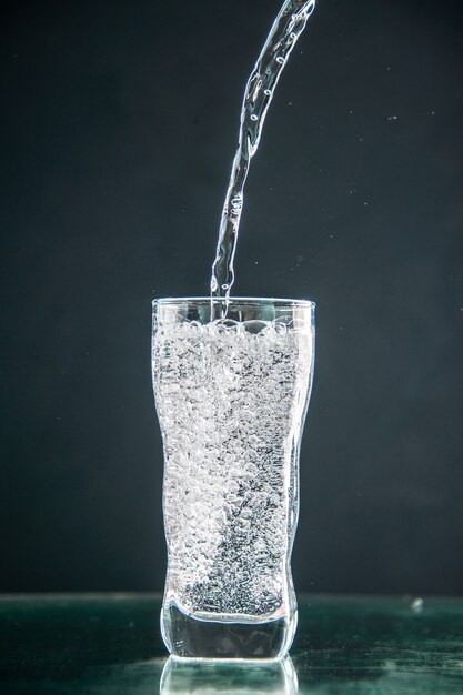 Vooraanzicht glas frisdrank dat op de donkere drank wordt gegoten foto champagne kerst water