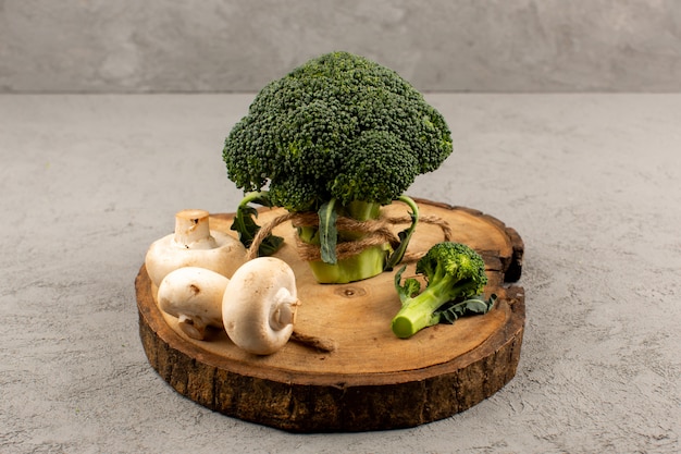 vooraanzicht groene broccoli paddestoelen op het bruine bureau en grijze vloer