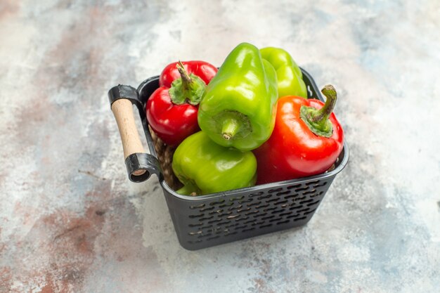 Vooraanzicht groene en rode paprika's in kom op naakte achtergrond vrije ruimte