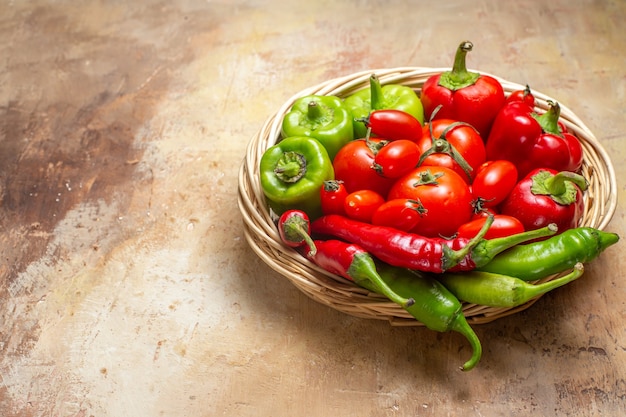 Vooraanzicht groene en rode pepers hete pepers tomaten in rieten mand op amberkleurige achtergrond vrije plaats