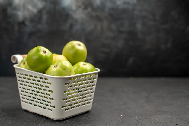 Vooraanzicht groene tomaten in mand op donkere achtergrond