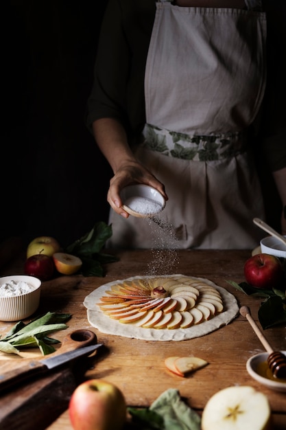 Vooraanzicht hand gietende suiker op appelschijfjes