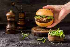 Gratis foto vooraanzicht hand met rundvlees hamburger met salade en spek