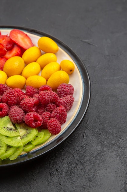 Gratis foto vooraanzicht heerlijk gesneden fruit in plaat op een donkere oppervlakte fruitboom exotische rijpe foto tropisch