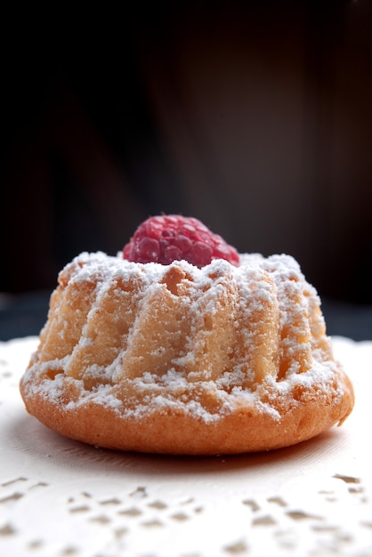 Gratis foto vooraanzicht heerlijke cake met room en rode framboos op het donkere zoete van het het fruitkoekje van de oppervlaktecake