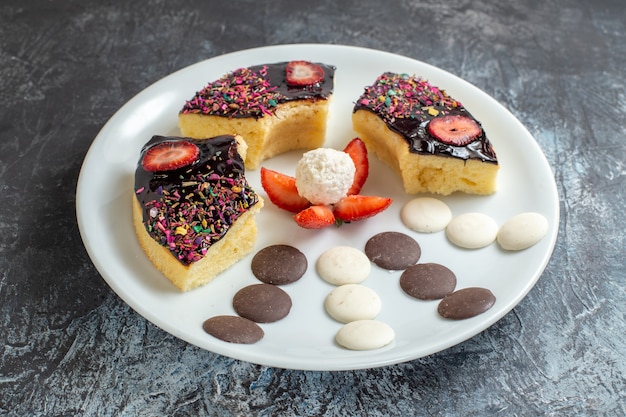 Vooraanzicht heerlijke cakeplakken met kleine koekjes op donkere achtergrond