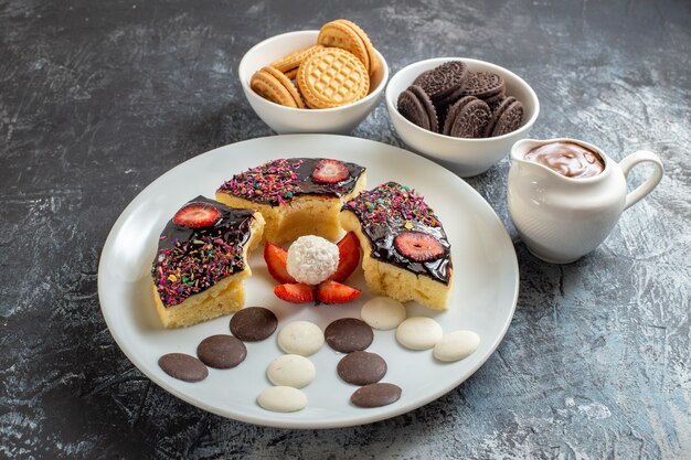 Vooraanzicht heerlijke cakeplakken met koekjes op de donkere achtergrond