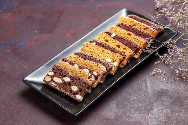 Vooraanzicht heerlijke cakeplakken met noten binnen cakevorm op donkere ruimte