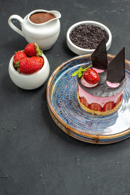 Vooraanzicht heerlijke cheesecake met aardbei en chocolade op ovale bordkommen met aardbeienchocolade op dark