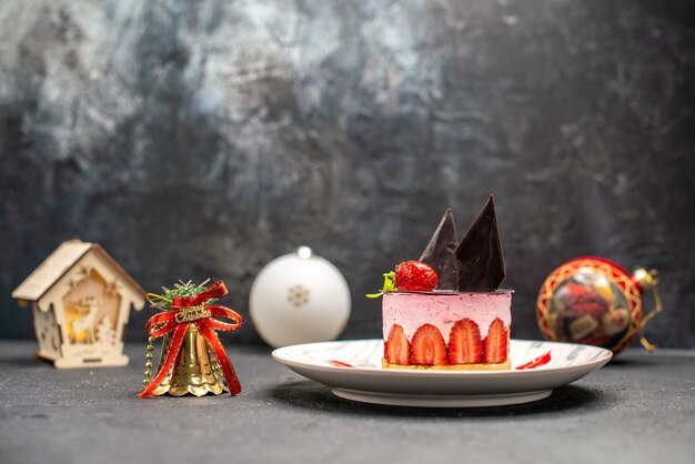 Vooraanzicht heerlijke cheesecake met aardbei en chocolade op ovale plaat kerst speelgoed lantaarn op dark