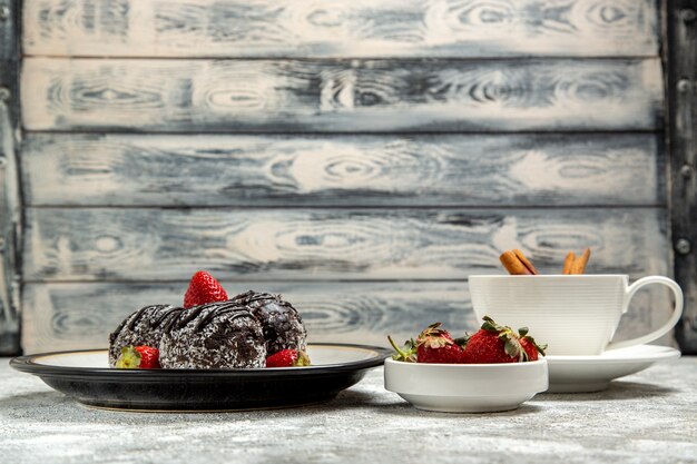 Vooraanzicht heerlijke chocoladetaarten met verse aardbeien op het witte oppervlak chocolade suiker koekje zoete cake bak koekje