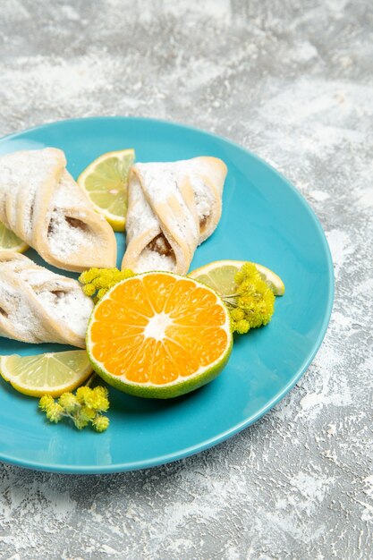 Vooraanzicht heerlijke deeg gebakjes met plakjes citroen op witte muur gebak suiker bakken cake deeg zoete taart