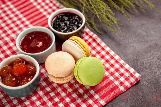 Vooraanzicht heerlijke franse macarons met fruitjams op donkere ondergrond zoete fruit marmelade cake biscuit zoete suiker