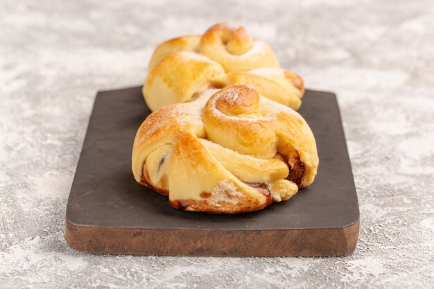 Vooraanzicht heerlijke fruitige zoete gebakjes gebakken op het grijze oppervlak cake gebak zoete bak thee