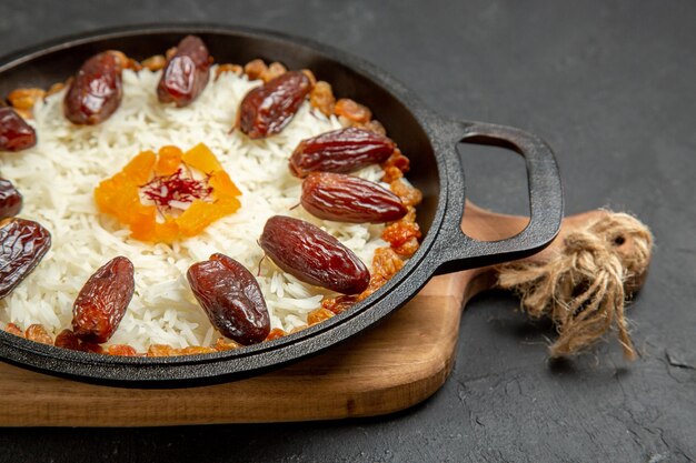 Vooraanzicht heerlijke gekookte plov-rijstmaaltijd met khurma en rozijnen op donkere ondergrond plov-rijstschotelmaaltijd koken