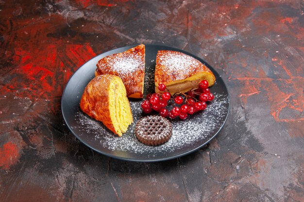 Gratis foto vooraanzicht heerlijke gesneden taart met rode bessen op de donkere tafel