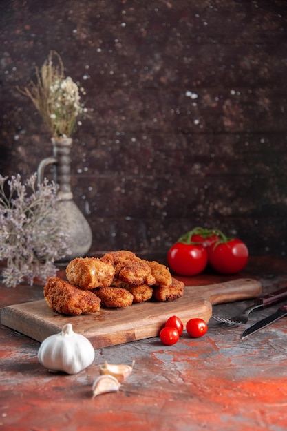 Vooraanzicht heerlijke kippenvleugels op snijplank met tomaten donkere achtergrond maaltijd diner eten sandwich hamburger vlees kleur friet salade gezondheid lunch