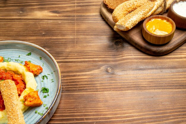 Vooraanzicht heerlijke kipplakken met aardappelpuree en brood op houten bureau aardappelmeel eten pittige peper