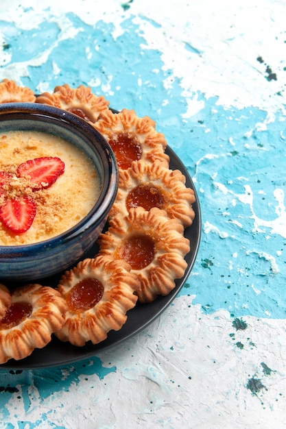 Vooraanzicht heerlijke koekjes met jam en aardbeidessert op blauwe muur Koekje suiker zoet koekje bakken theecake