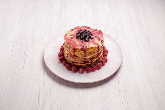 Vooraanzicht heerlijke pannenkoeken met aardbeien en gelei op een witte taartkoekje met zoete bessenvruchtencake