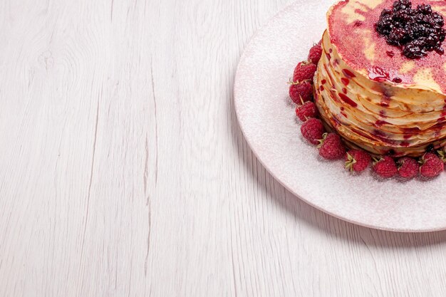 Vooraanzicht heerlijke pannenkoeken met aardbeien en gelei op licht wit bureautaartkoekje, zoete bessenfruitcake