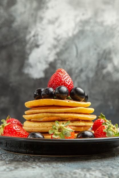 Vooraanzicht heerlijke pannenkoeken met fruit en bessen op het dessert van de donkere fruitcake