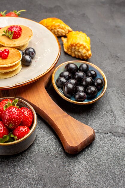 Vooraanzicht heerlijke pannenkoeken met fruit op donkere oppervlakte cake fruit zoete taart