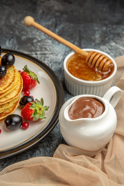 Vooraanzicht heerlijke pannenkoeken met honing en fruit op het lichte oppervlak cake zoet fruit