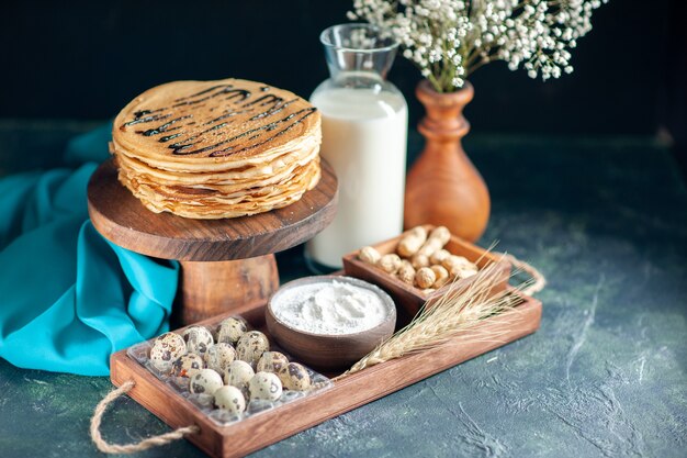 Vooraanzicht heerlijke pannenkoeken met noten op de donkerblauwe ochtendtaart dessert zoete cake honing ontbijt melk