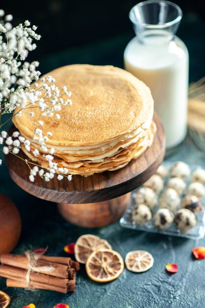Vooraanzicht heerlijke pannenkoeken op houten bureau en donkere ontbijttaart, zoete honingthee dessertmelk