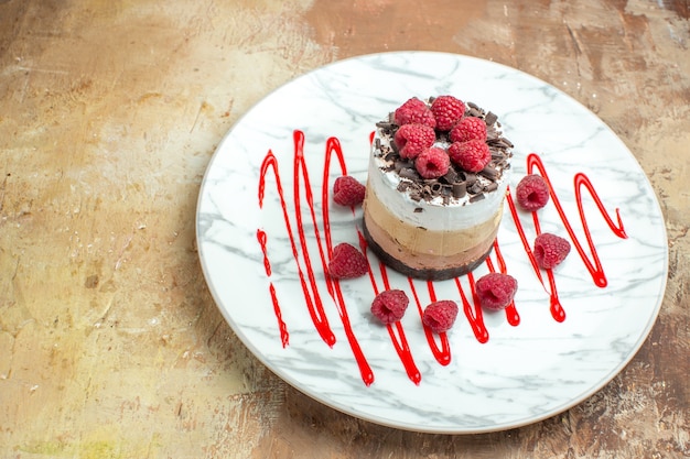 Gratis foto vooraanzicht heerlijke romige cake in bord met frambozen op bruine tafel