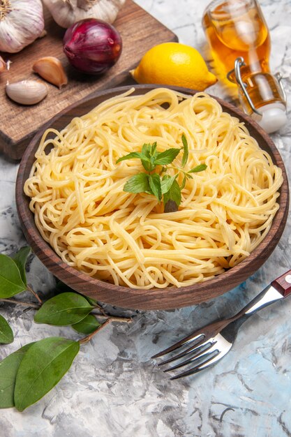 Vooraanzicht heerlijke spaghetti met knoflook op een witte tafel pasta deeg maaltijd peper