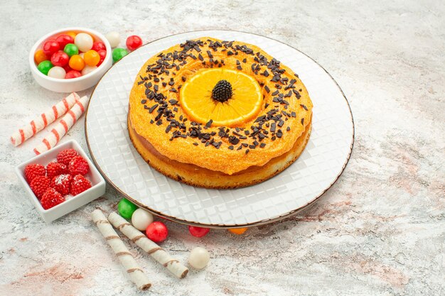 Vooraanzicht heerlijke taart met kleurrijke snoepjes op witte achtergrond taart biscuit zoete dessert regenboog dessert