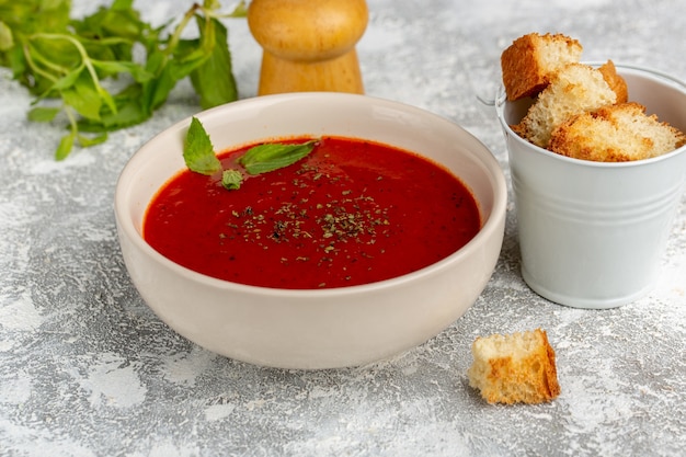 Vooraanzicht heerlijke tomatensoep met brood beschuit en greens op grijs, soep maaltijd diner groente
