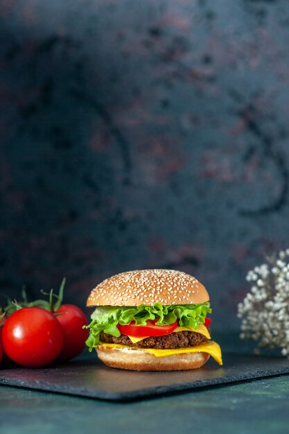 vooraanzicht heerlijke vlees hamburger met rode tomaten op donkere achtergrond