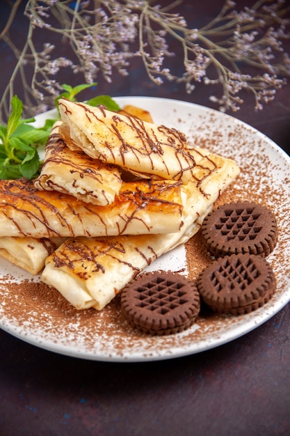 Gratis foto vooraanzicht heerlijke zoete gebakjes met chocoladekoekjes op donkere ruimte