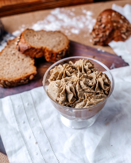 Vooraanzicht ijs chocolade in transparant plastic glas samen met verse sneetjes brood op de bruine vloer